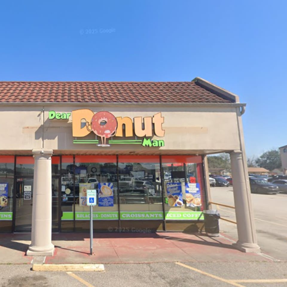 Exterior of Dear Donut Man, a donut shop with a large sign featuring a donut character.