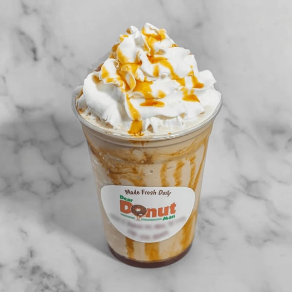 A Dear Donut Man caramel frappe with whipped cream and caramel drizzle on a marble surface.